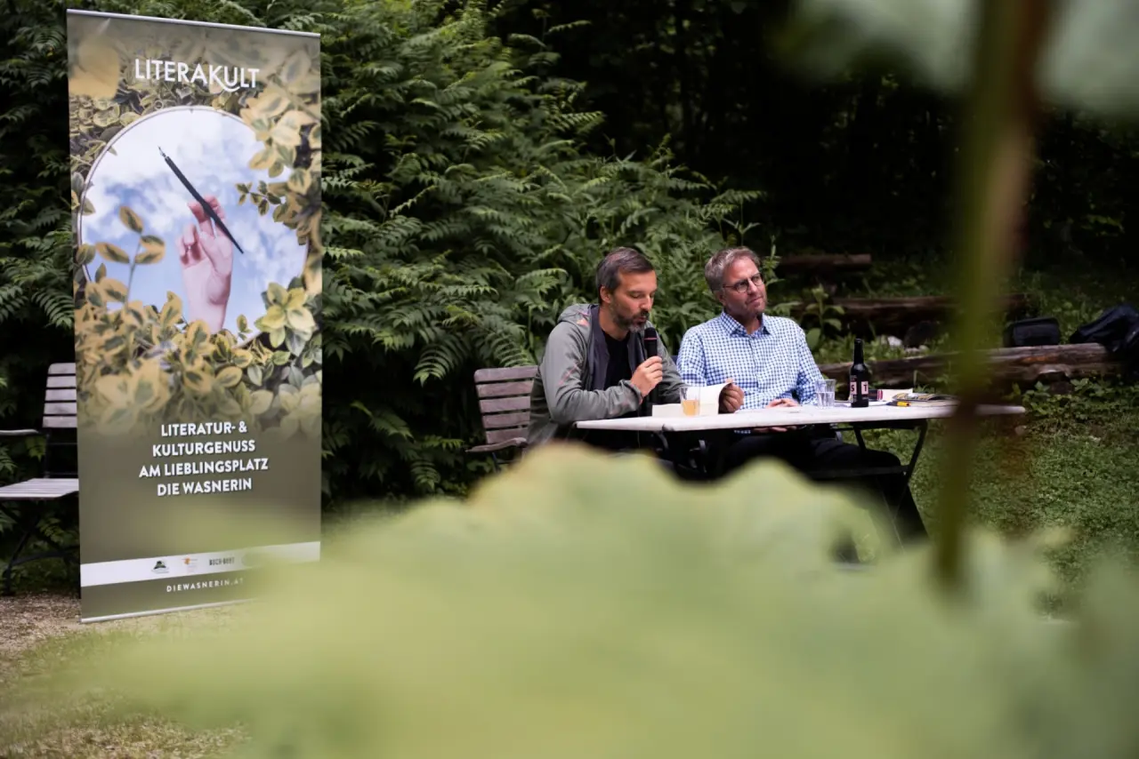 Kulturelles Event 'LITERAKULT' im Garten des Hotel DIE WASNERIN mit zwei Rednern und Banner.
