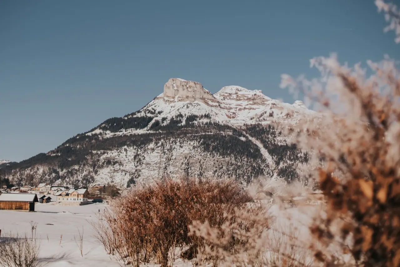 Verschneite Berglandschaft mit majestätischem Gipfel und Häusern im Tal, die Umgebung des Hotel DIE WASNERIN.
