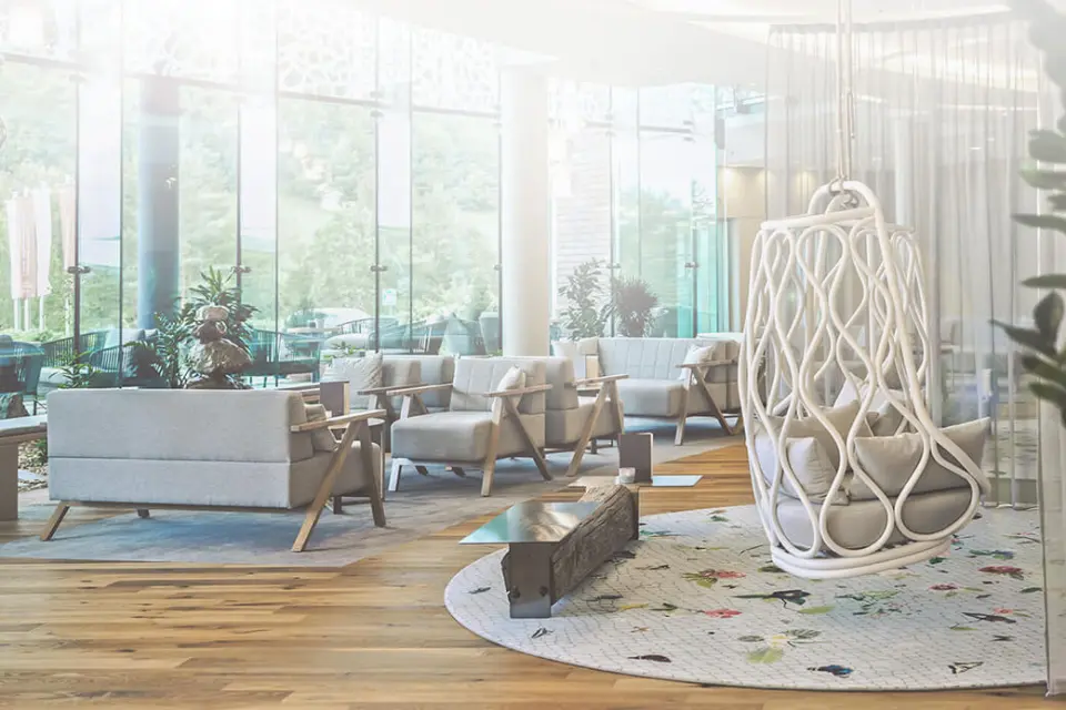 Helle, moderne Lobby mit bequemen Sitzgelegenheiten und Hängesessel im Hotel Das Sonnreich, umgeben von Natur.