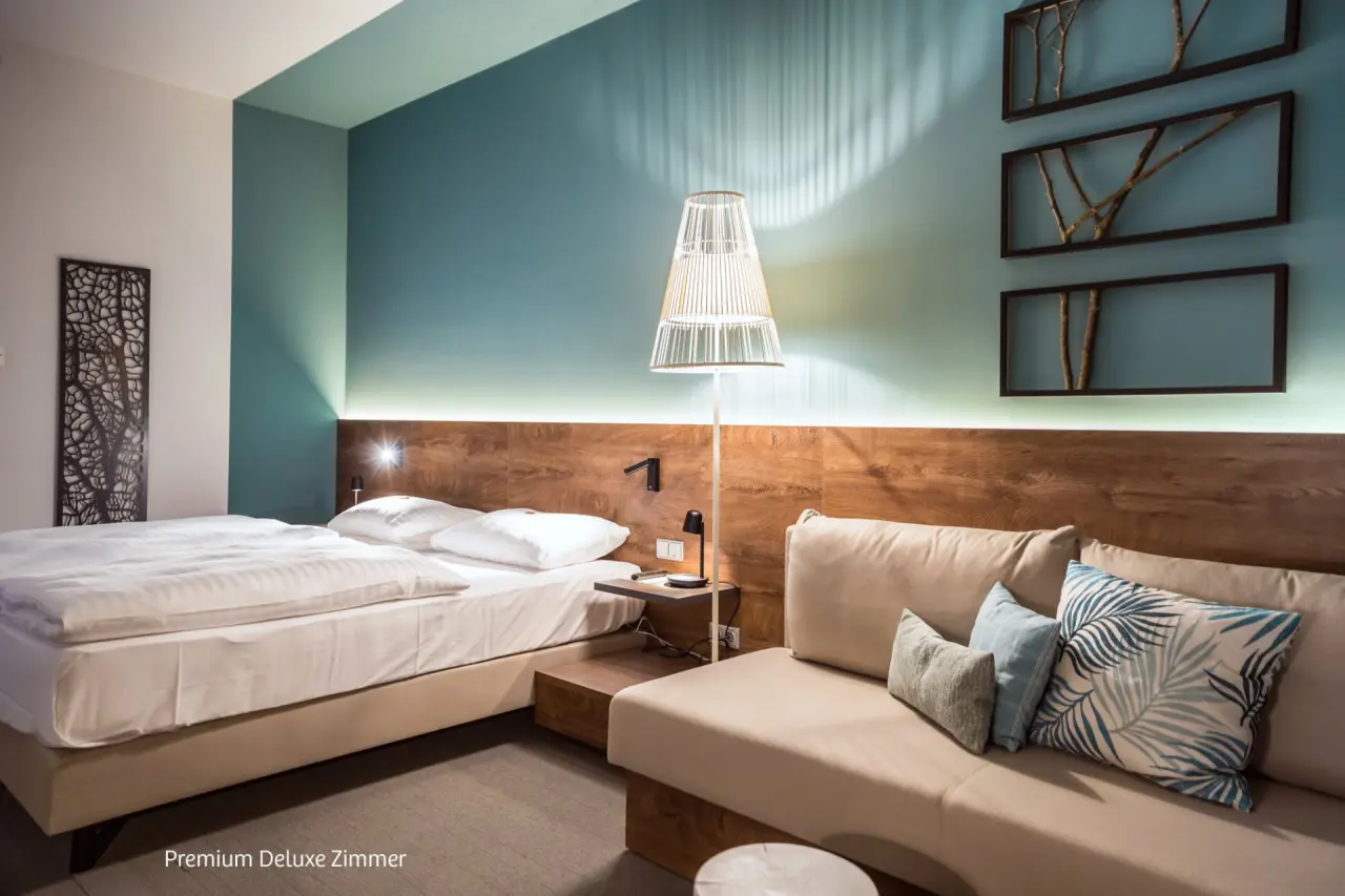 Premium Deluxe Zimmer im Hotel Das Sonnreich mit komfortablem Bett, Sofa und moderner Einrichtung.