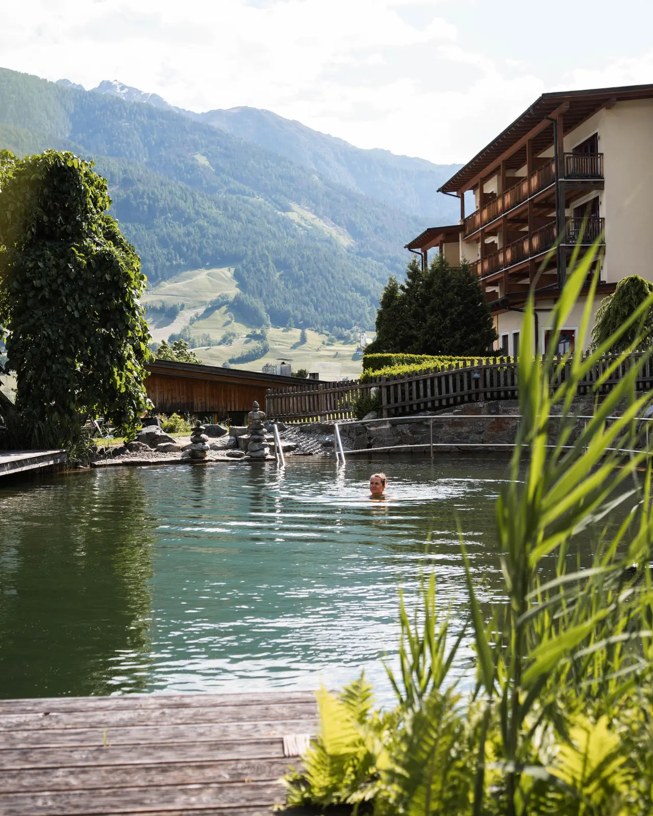 Naturbadeteich mit Schwimmerin und Alpenpanorama am Naturhotel Outside