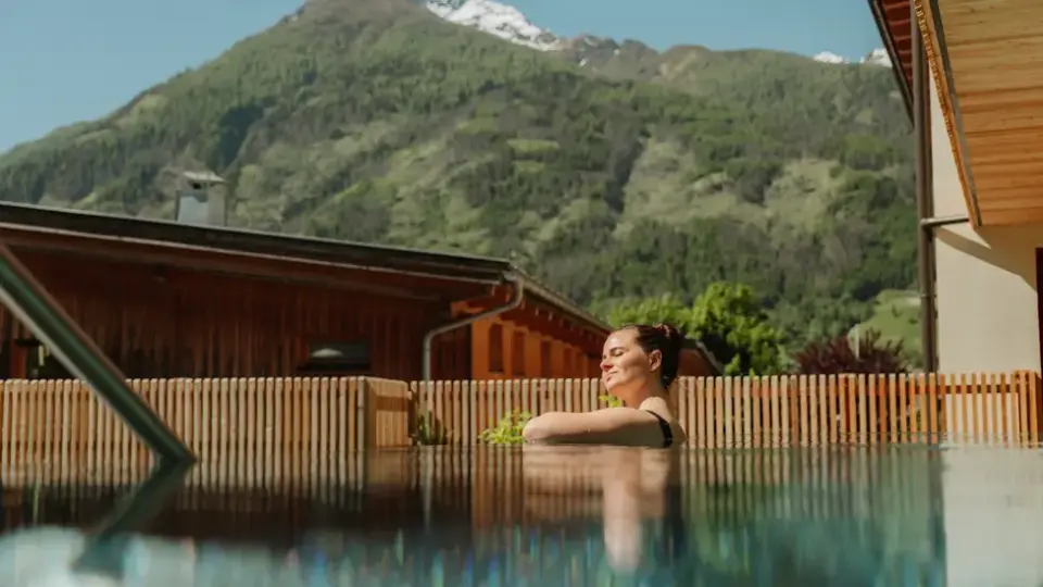 Entspannende Badegäste im Aussenpool des Naturhotel Outside mit Blick auf die umliegende Berglandschaft.