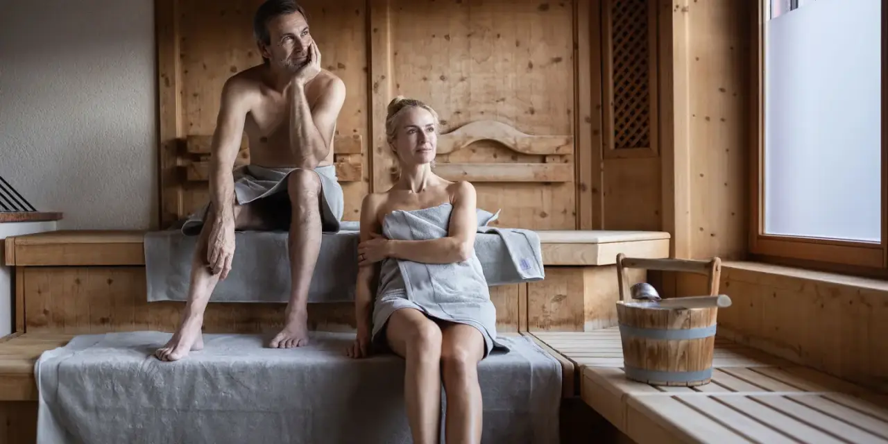 Paar genießt die Wärme in der finnischen Holzsauna des Naturhotel Outside. Perfekte Entspannung im Wellnessbereich.