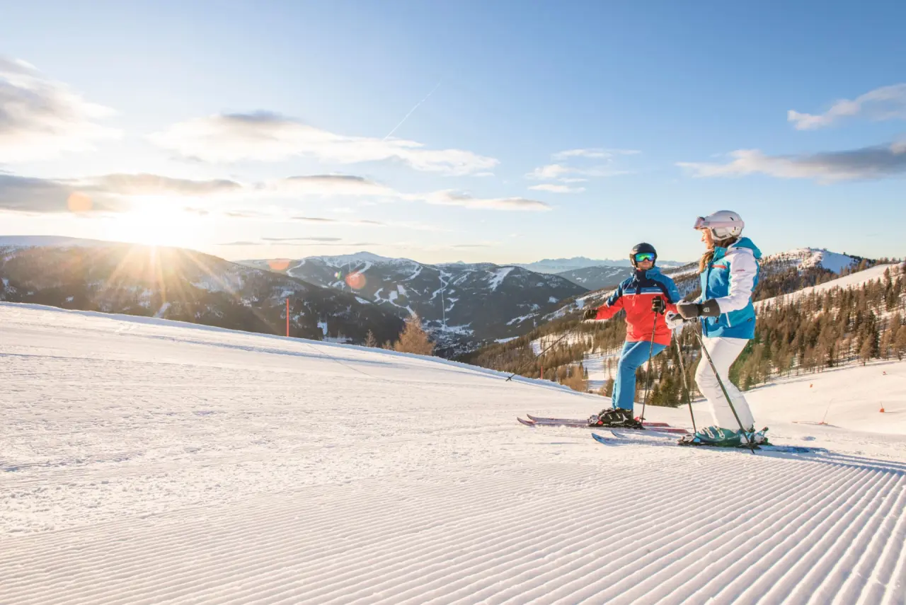 Skifahrer auf frisch präparierter Piste mit Sonnenuntergang und Bergpanorama am Hotel GUT Trattlerhof & Chalets.