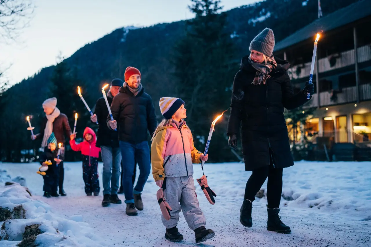 Familien-Fackelwanderung im Schnee vor dem Hotel GUT Trattlerhof & Chalets****
