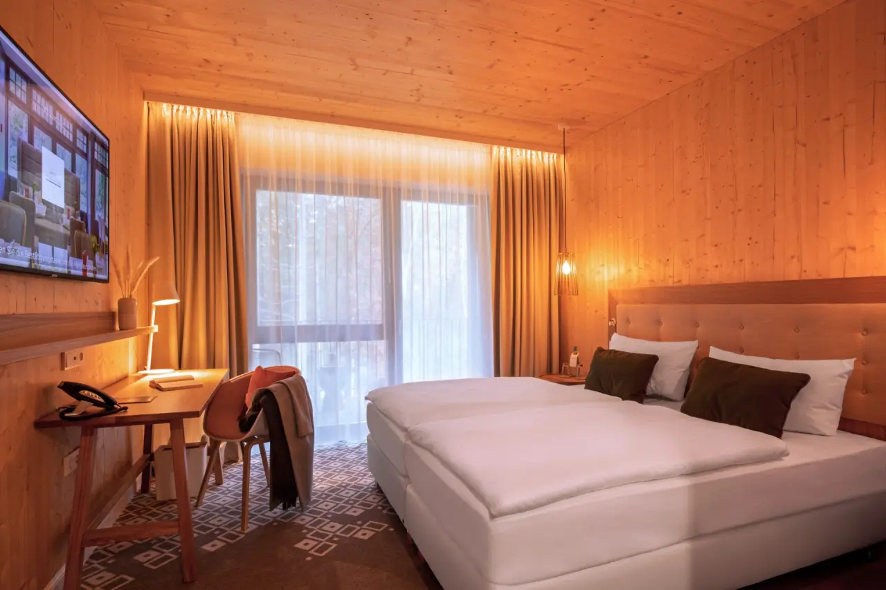 Gemütliches Doppelzimmer mit Holzelementen, Schreibtisch und Blick ins Grüne im Hotel Heidegrund.