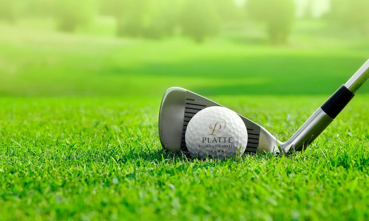 Golfball mit Romantik Hotel Haus Platte Logo und Golfschläger auf grünem Golfplatz.