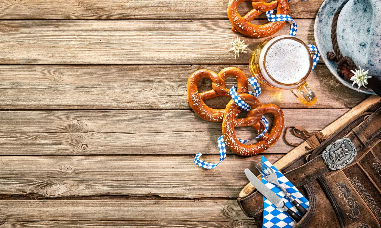 Bayerische Spezialitäten wie Brezeln und Bier mit Trachten-Accessoires auf Holztisch im Romantik Hotel Haus Platte.