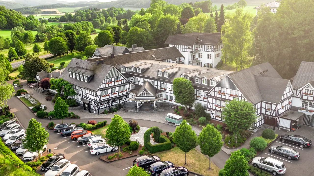 Luftaufnahme des Romantik Hotel Haus Platte mit traditioneller Fachwerkarchitektur, umgeben von grünen Wäldern und Wiesen.