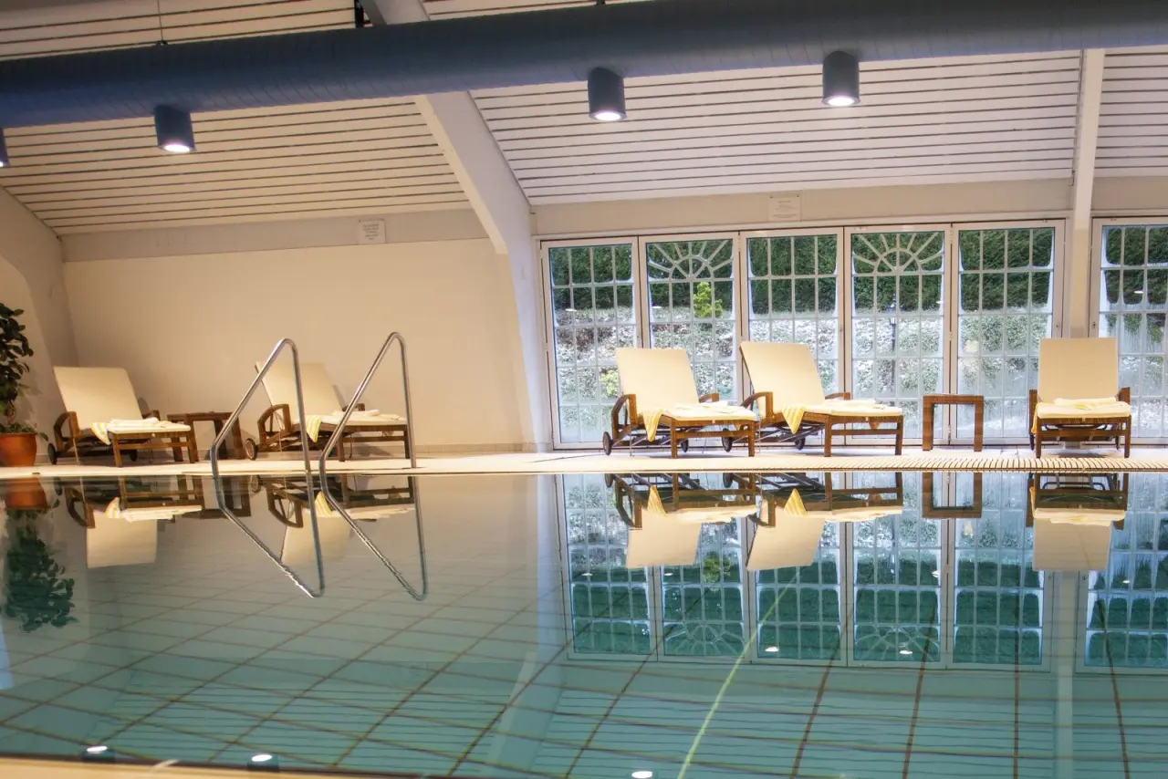 Innenpool mit Liegestühlen und Blick auf die winterliche Natur im Romantik Hotel Haus Platte.