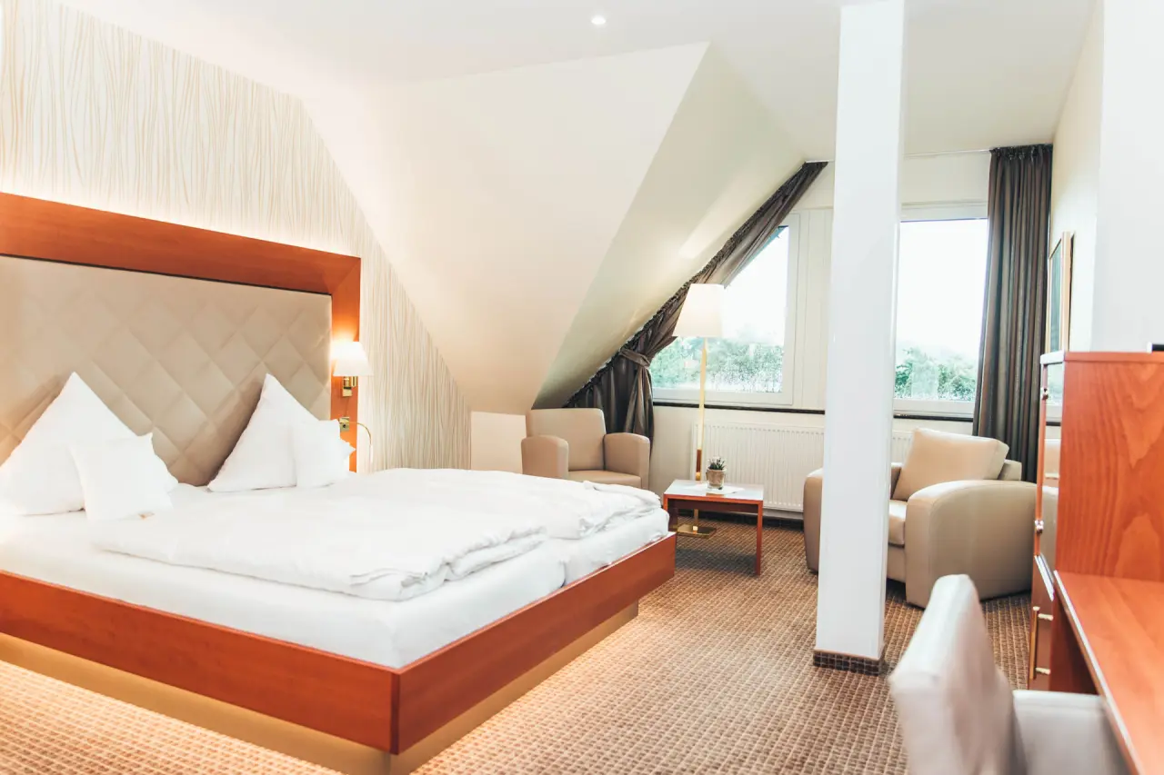 Gemütliches Doppelzimmer mit Dachschräge und Sitzbereich im Ringhotel Teutoburger Wald, ideal für Erholung.