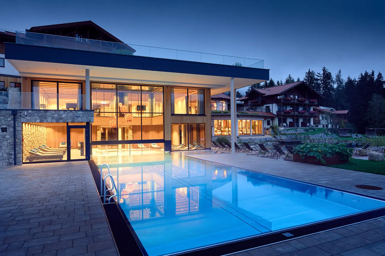 Abendliche Aussenansicht des Gut Sonnberghof Naturhotel mit beleuchtetem Aussenpool und moderner Spa-Architektur.