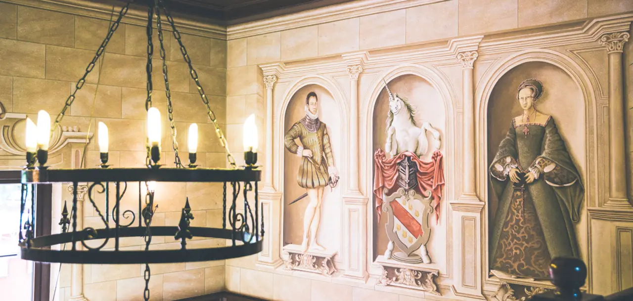 Wandgemälde mit historischen Figuren und Wappen im The Lakeside Burghotel zu Strausberg, beleuchtet von einem Kronleuchter.