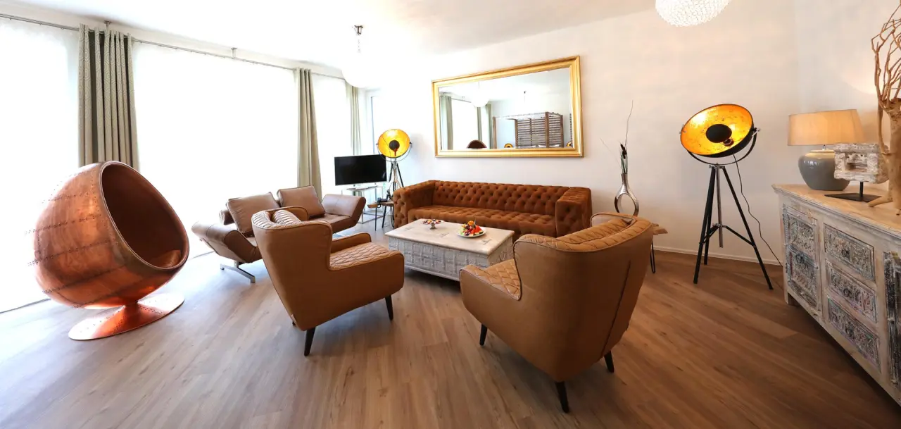Stilvolles Wohnzimmer einer Suite im The Lakeside Burghotel zu Strausberg mit Chesterfield Sofa und Design-Sessel.