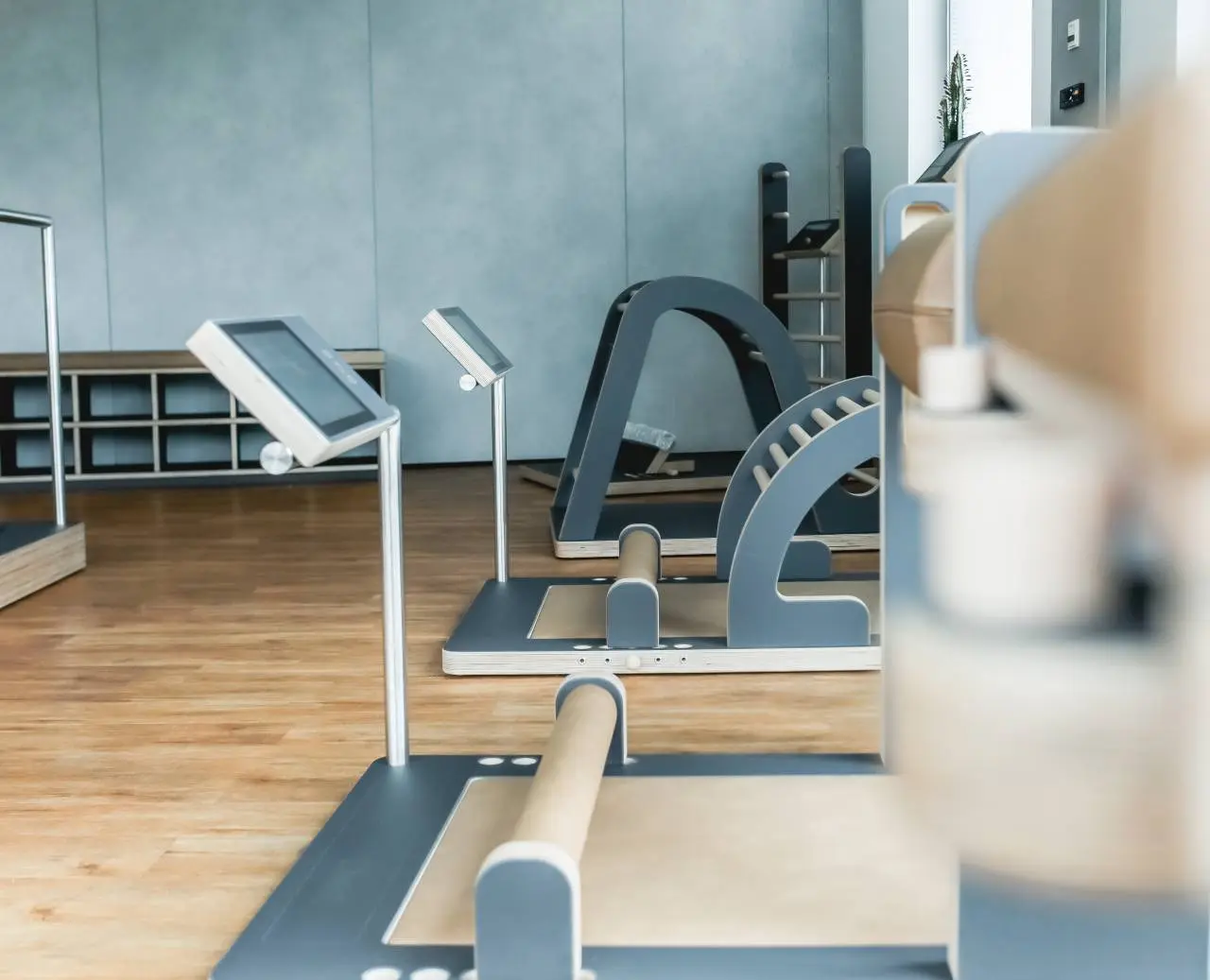 Moderner Fitnessbereich mit stilvollen Holz- und Grautönen sowie innovativen Geräten im Hotel am Vitalpark.