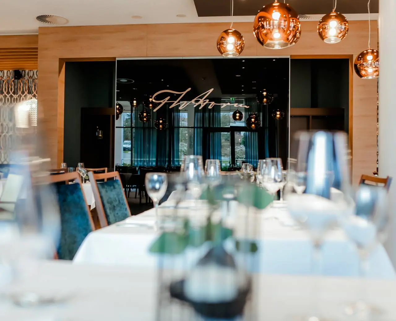 Elegantes Restaurant im Hotel am Vitalpark mit stilvoll gedeckten Tischen und modernen Kupferlampen.