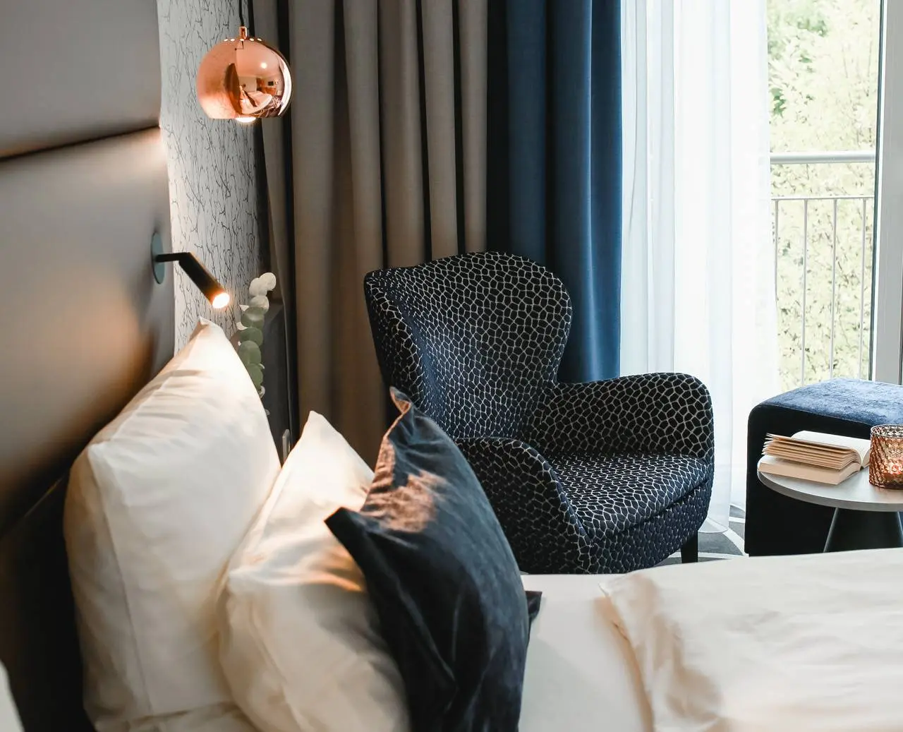 Gemütliches Hotelzimmer im Hotel am Vitalpark mit Sessel, Bett und Balkonzugang.