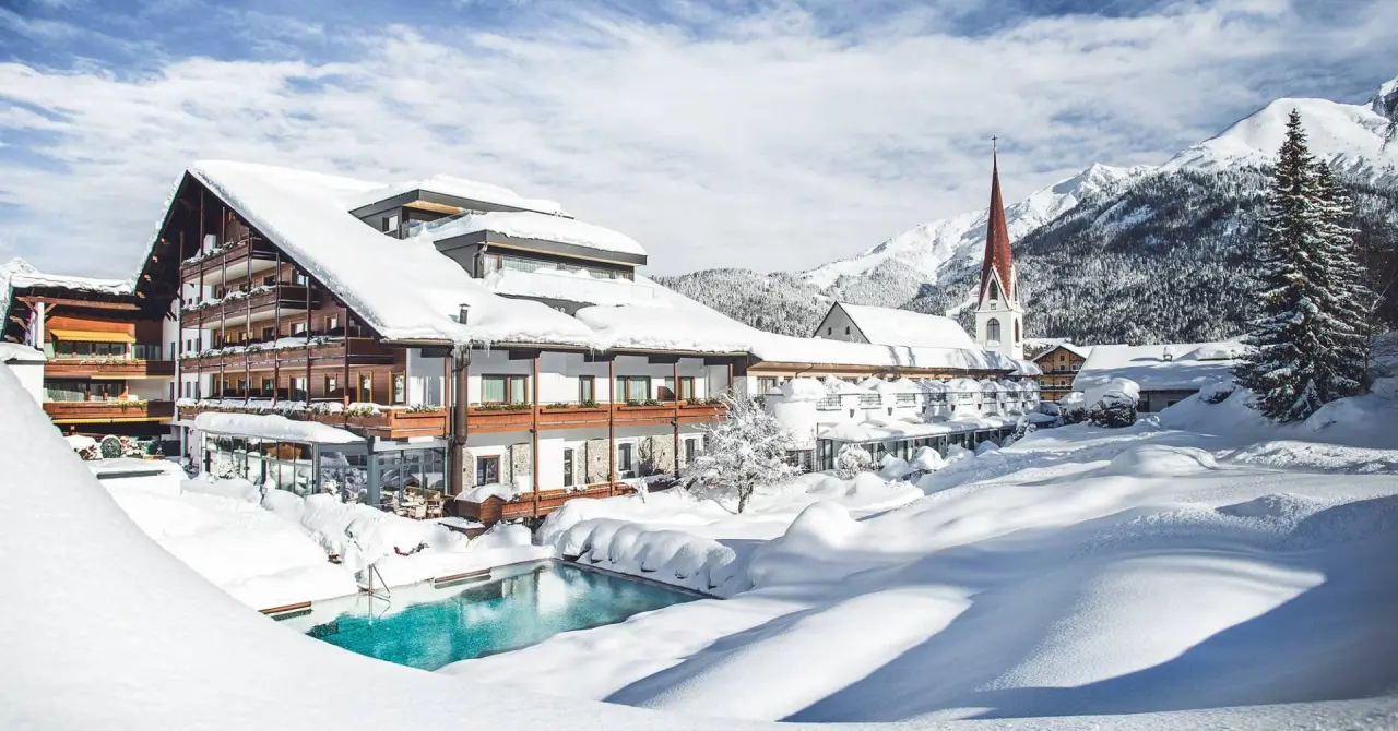 Hotel Kosterbräu im Winter mit verschneiter Fassade, beheiztem Aussenpool und Alpenpanorama.