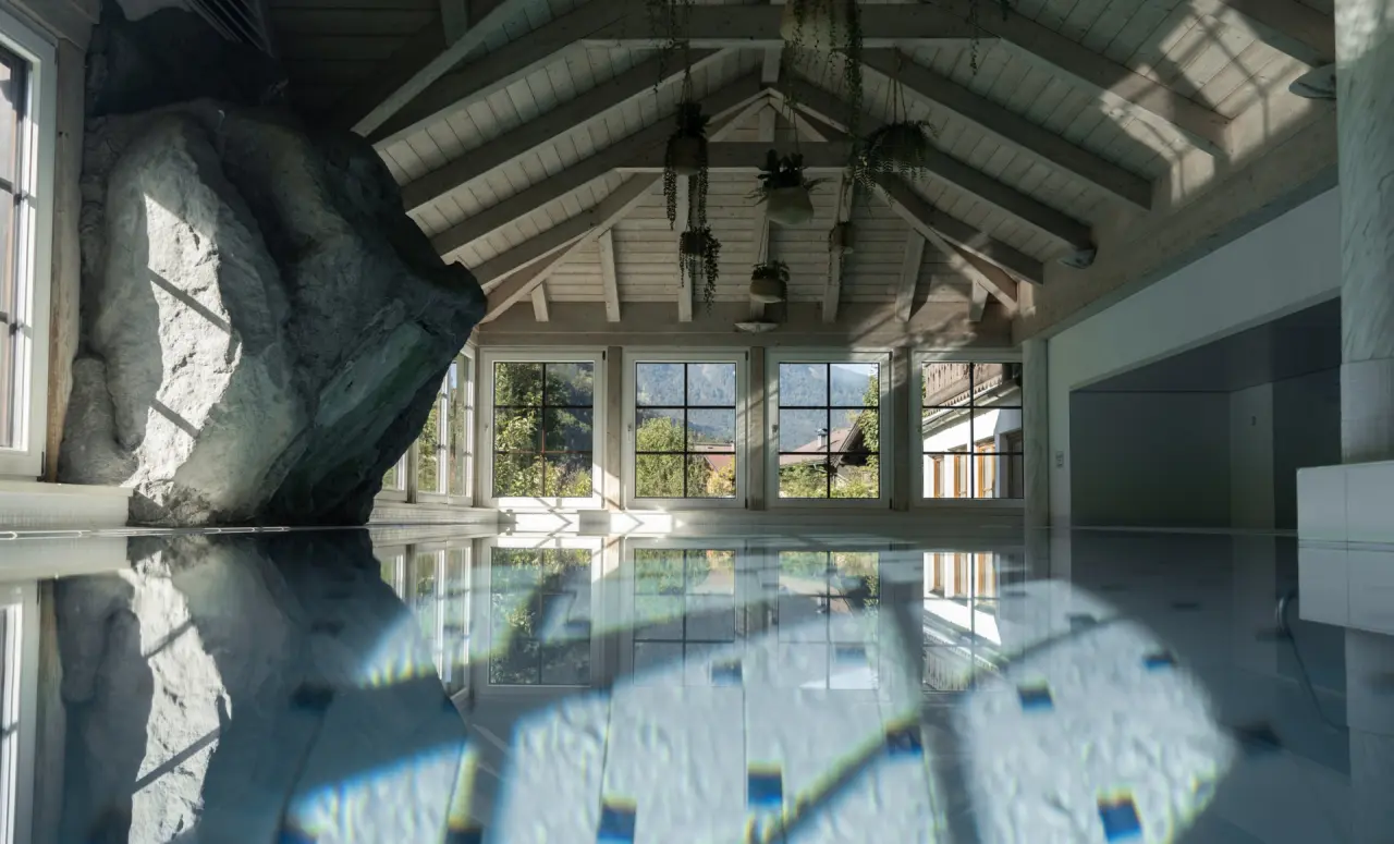 Naturnaher Indoor-Pool mit Felswand, Holzdecke und Bergblick im Bergrose Hideaway Hotel.
