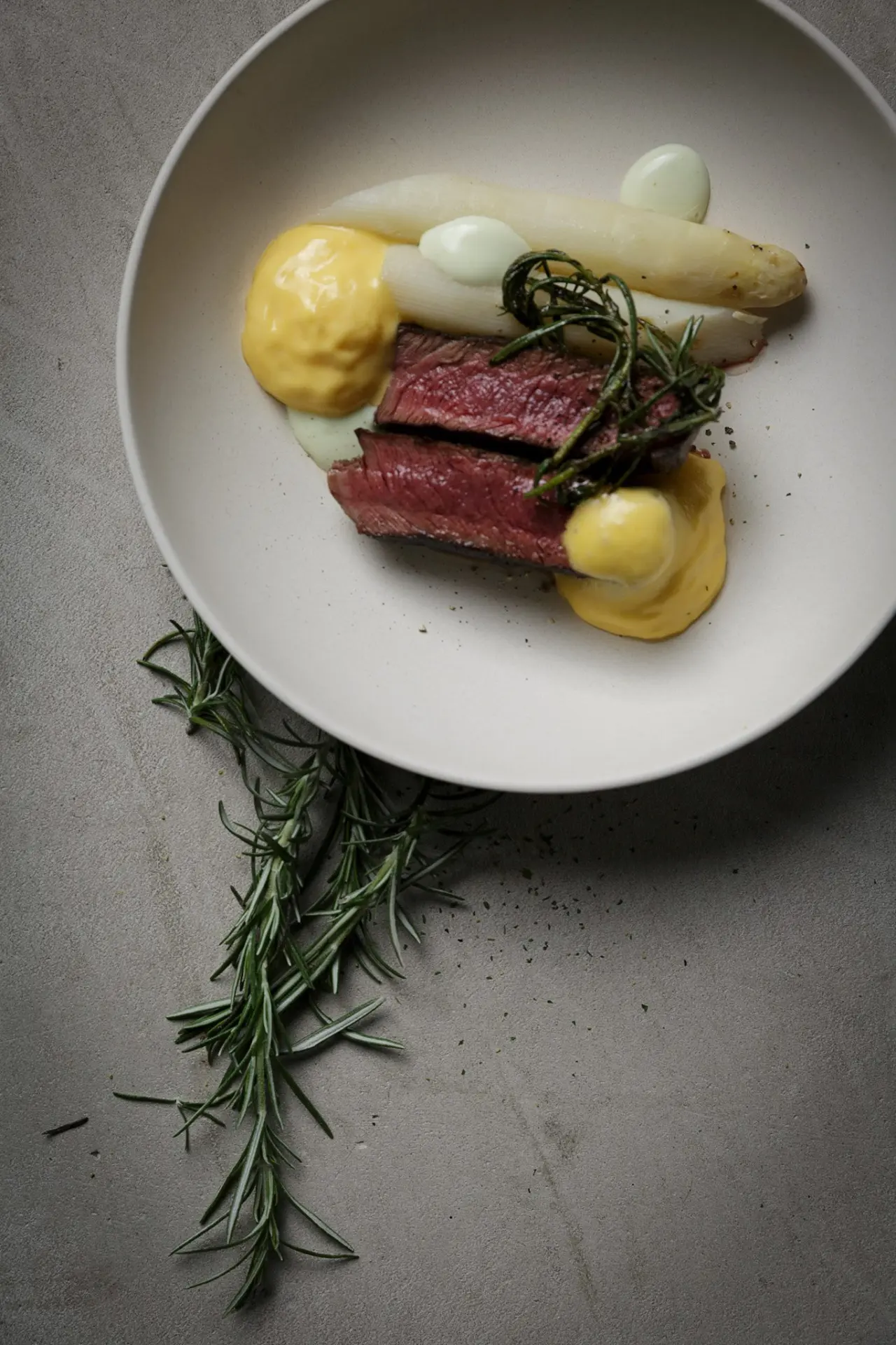 Gourmet-Gericht mit rosa gebratenem Steak, Spargel und Sauce im Restaurant des Bergrose Hideaway.