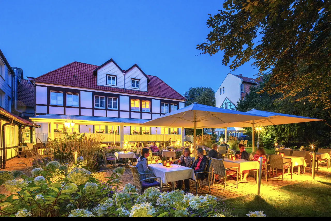 Gemütliche Abendstimmung auf der beleuchteten Gartenterrasse des Hotel Braunschweiger Hof mit Gästen beim Abendessen.