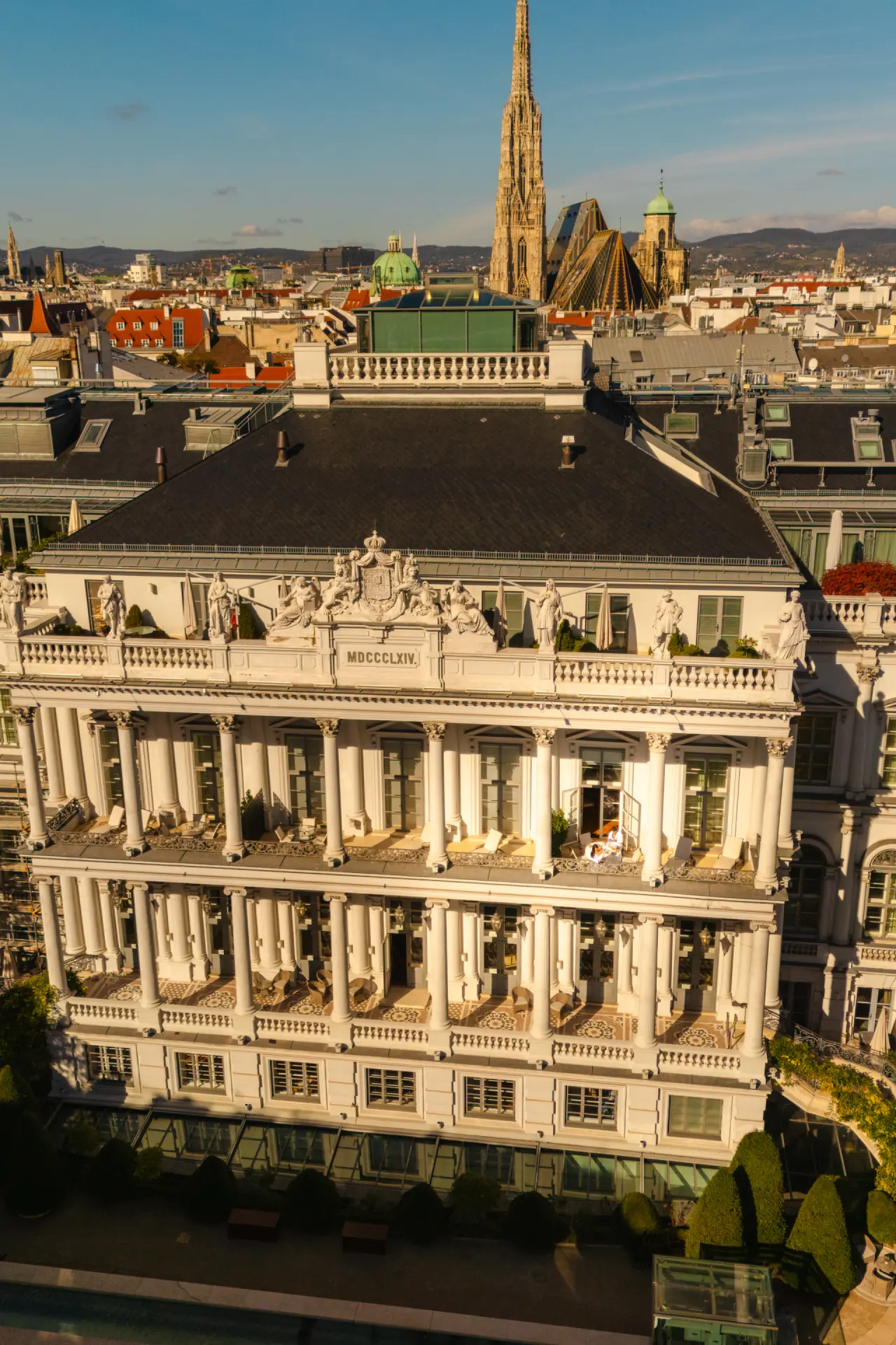 Luftaufnahme des Palais Coburg Residenz in Wien mit historischer Architektur und Stephansdom im Hintergrund bei Sonnenlicht.