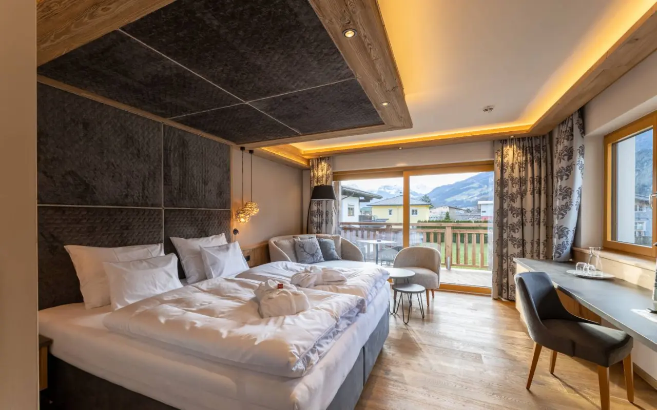 Modernes Doppelzimmer im Hotel Wöscherhof mit Balkon, Bergblick und Bademänteln für entspannte Wellnessmomente.