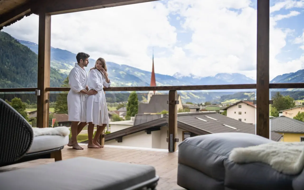 Paar in Bademänteln auf dem Balkon mit Bergblick im Hotel Wöscherhof. Entspannung und Alpenpanorama.