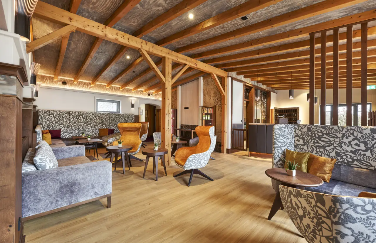 Einladende Hotellobby mit Holzbalken, bequemen Sitzgelegenheiten und warmem Licht im Wellness- und Vitalhotel Böhmhof.
