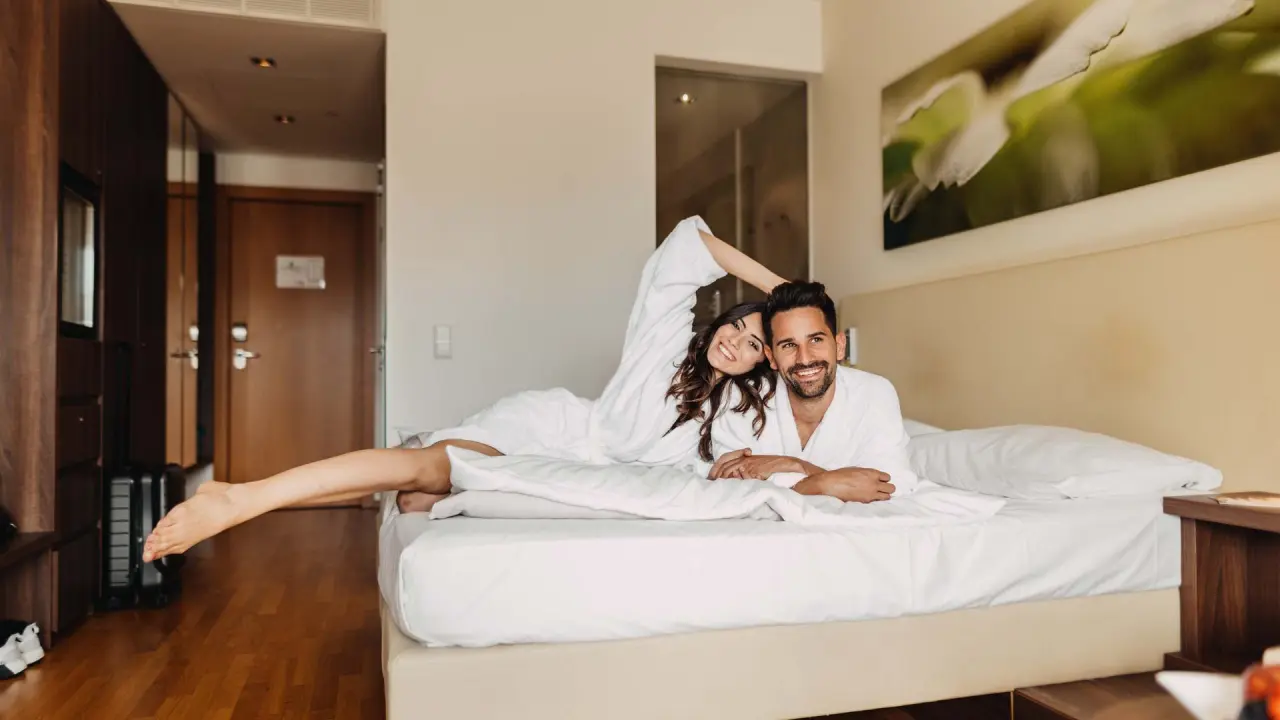 Glückliches Paar in Bademänteln entspannt im komfortablen Hotelzimmer des Thermenhotel Karawankenhof.