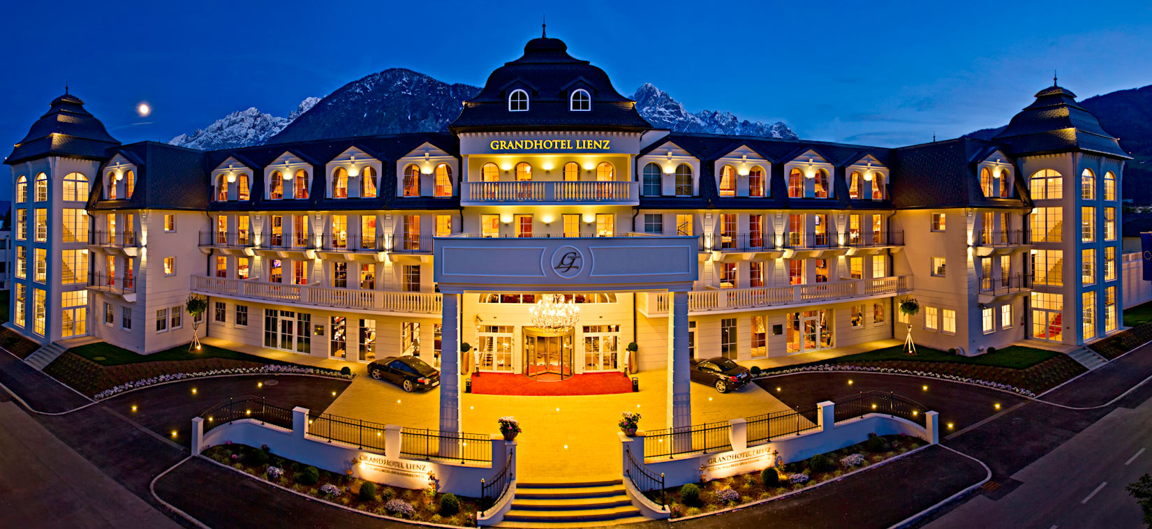 Grandhotel Lienz in Lienz – Beleuchtete Fassade bei Nacht mit Bergsilhouette | Wellnesshotel Osttirol