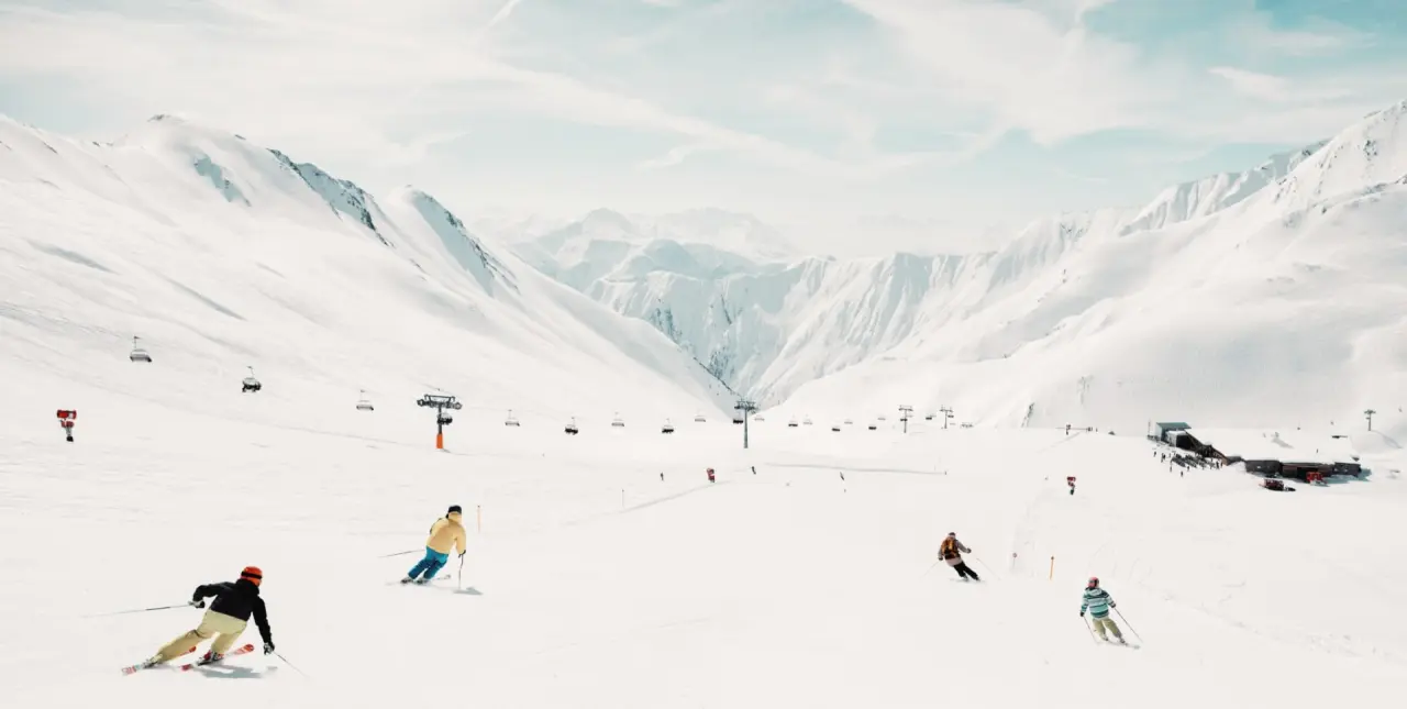 Skifahrer auf einer breiten Piste mit majestätischem Bergpanorama im Skigebiet nahe Hotel Universo.