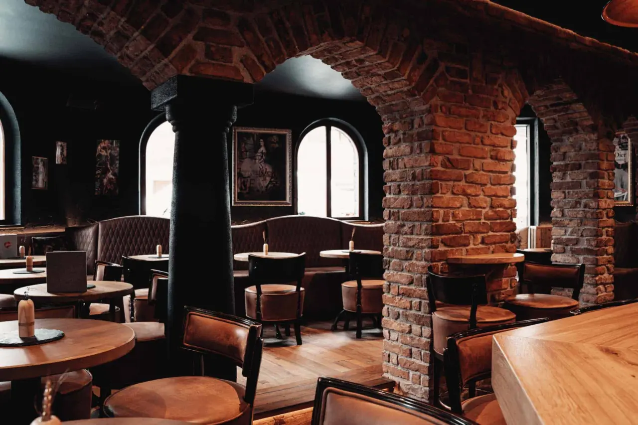 Rustikales Restaurant oder Bar im Hotel Universo mit Backsteinbögen, Holztischen und Ledersesseln.