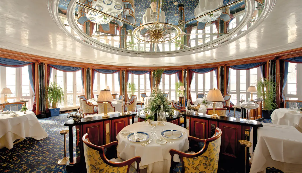 Elegantes, rundes Restaurant im Hotel Haus Dollenberg mit festlich gedeckten Tischen und grosser Spiegeldecke.