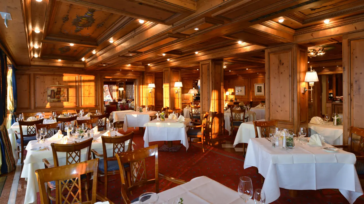 Traditionelles Restaurant im Hotel Haus Dollenberg mit Holztäfelung, festlich gedeckten Tischen und warmem Licht.