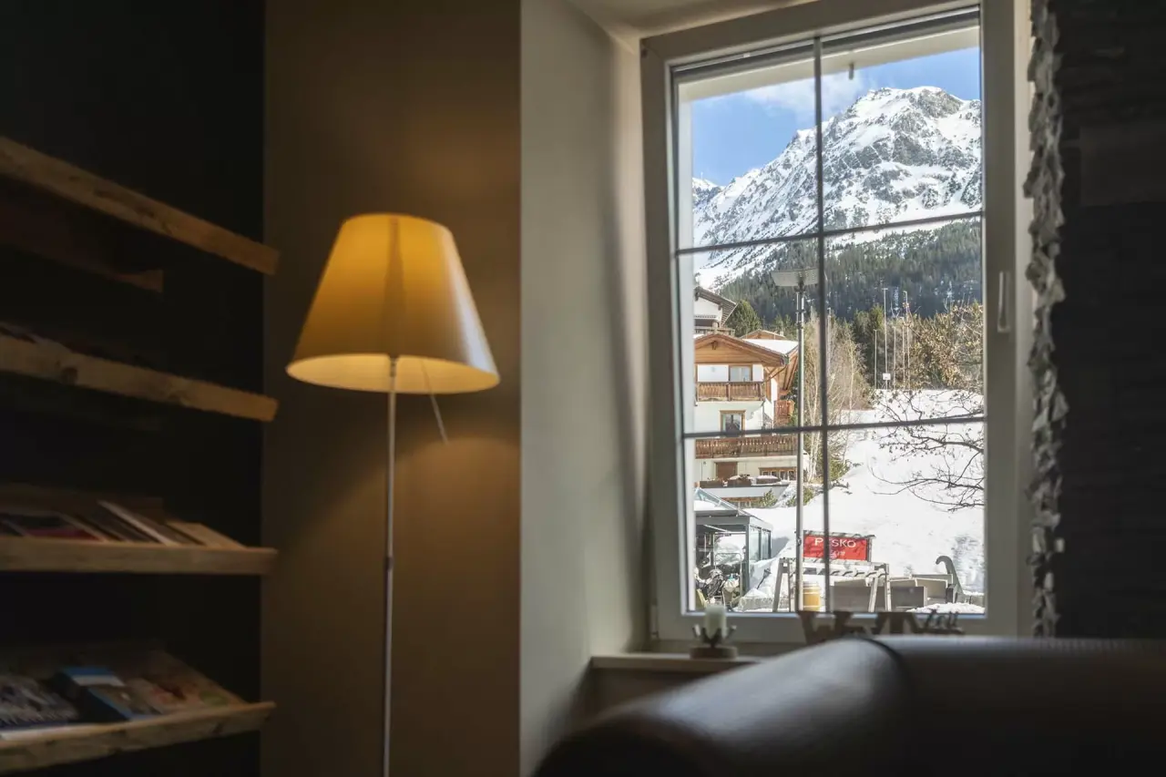 Gemütlicher Loungebereich im HOTEL LENZERHORN mit Blick auf die verschneiten Berge und alpine Umgebung.