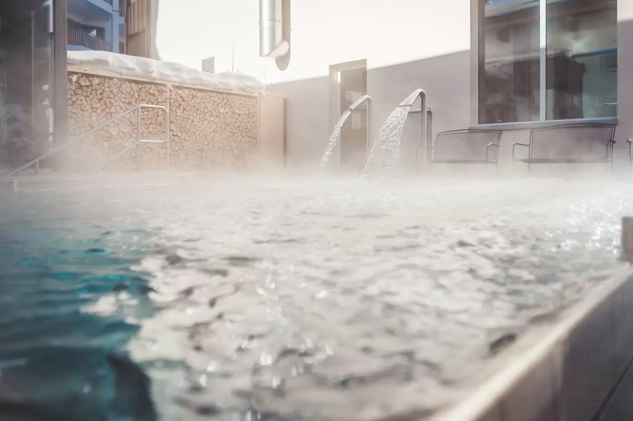 Beheizter Aussenpool mit Wasserspeiern und Dampf im Winter im Hotel Lenzerhorn.