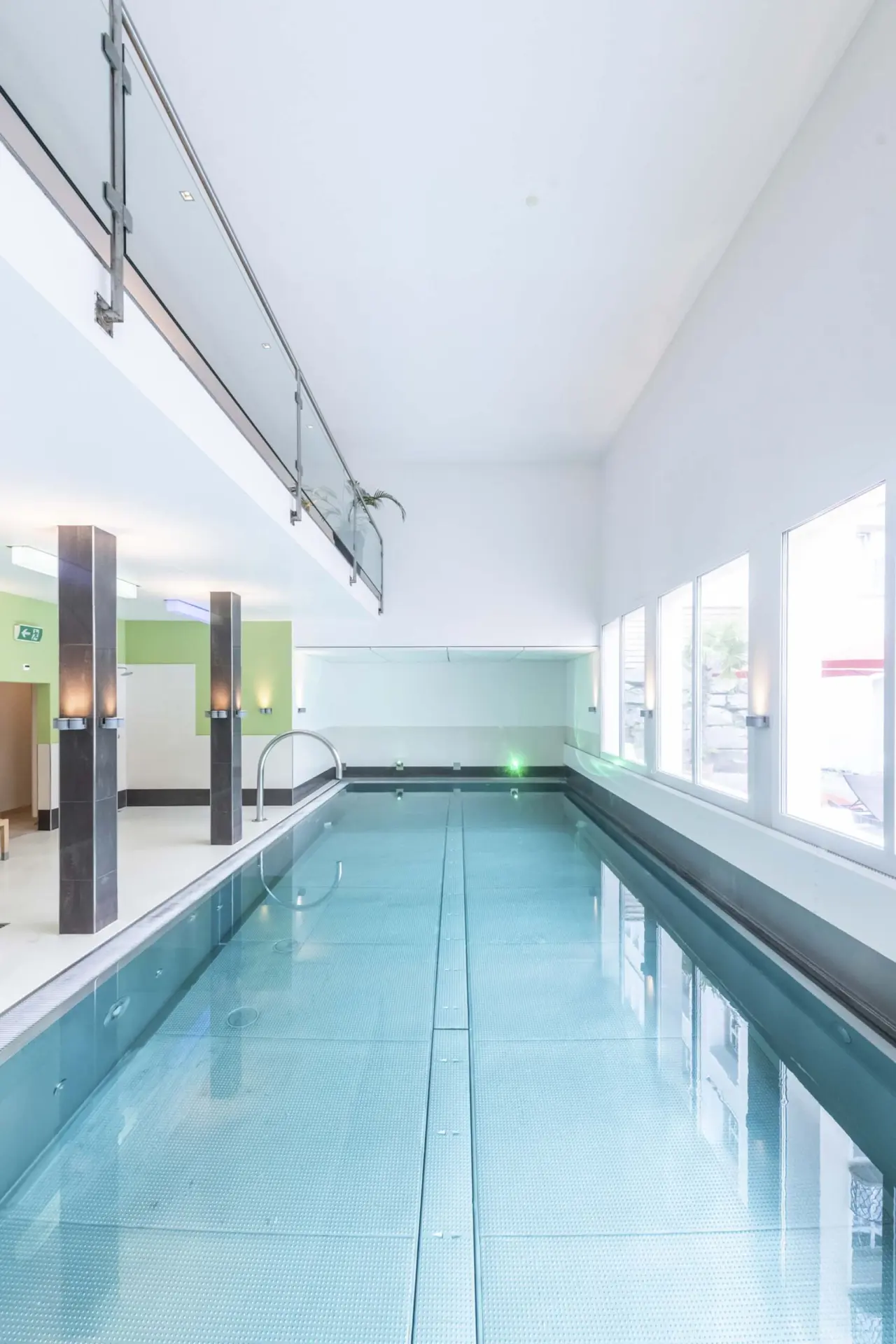 Heller Innenpool mit großen Fenstern und moderner Gestaltung im Wellnessbereich des HOTEL LENZERHORN.