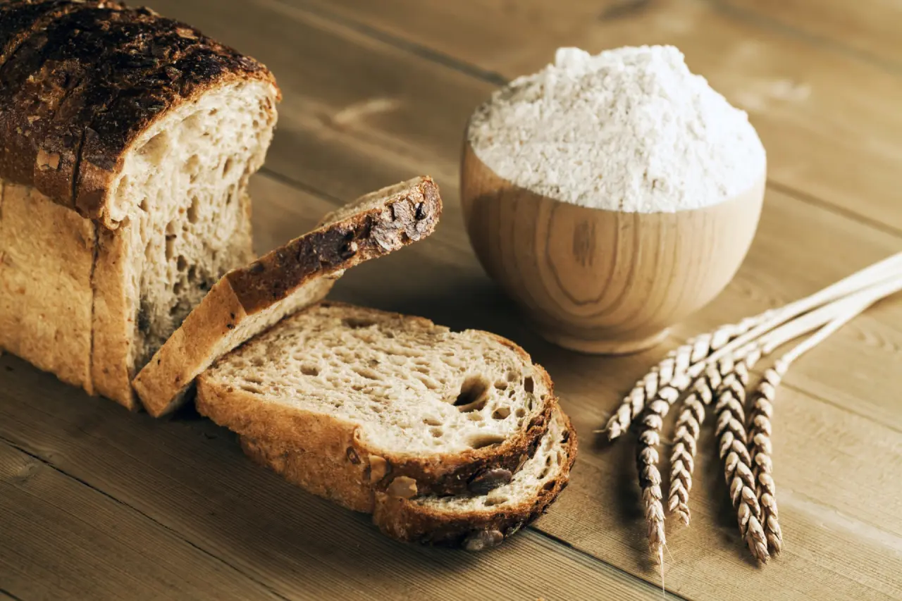 Frisch gebackenes Brot, Mehl und Weizenähren auf Holz im Aktiv- & Wellnesshotel Pirchnerhof.