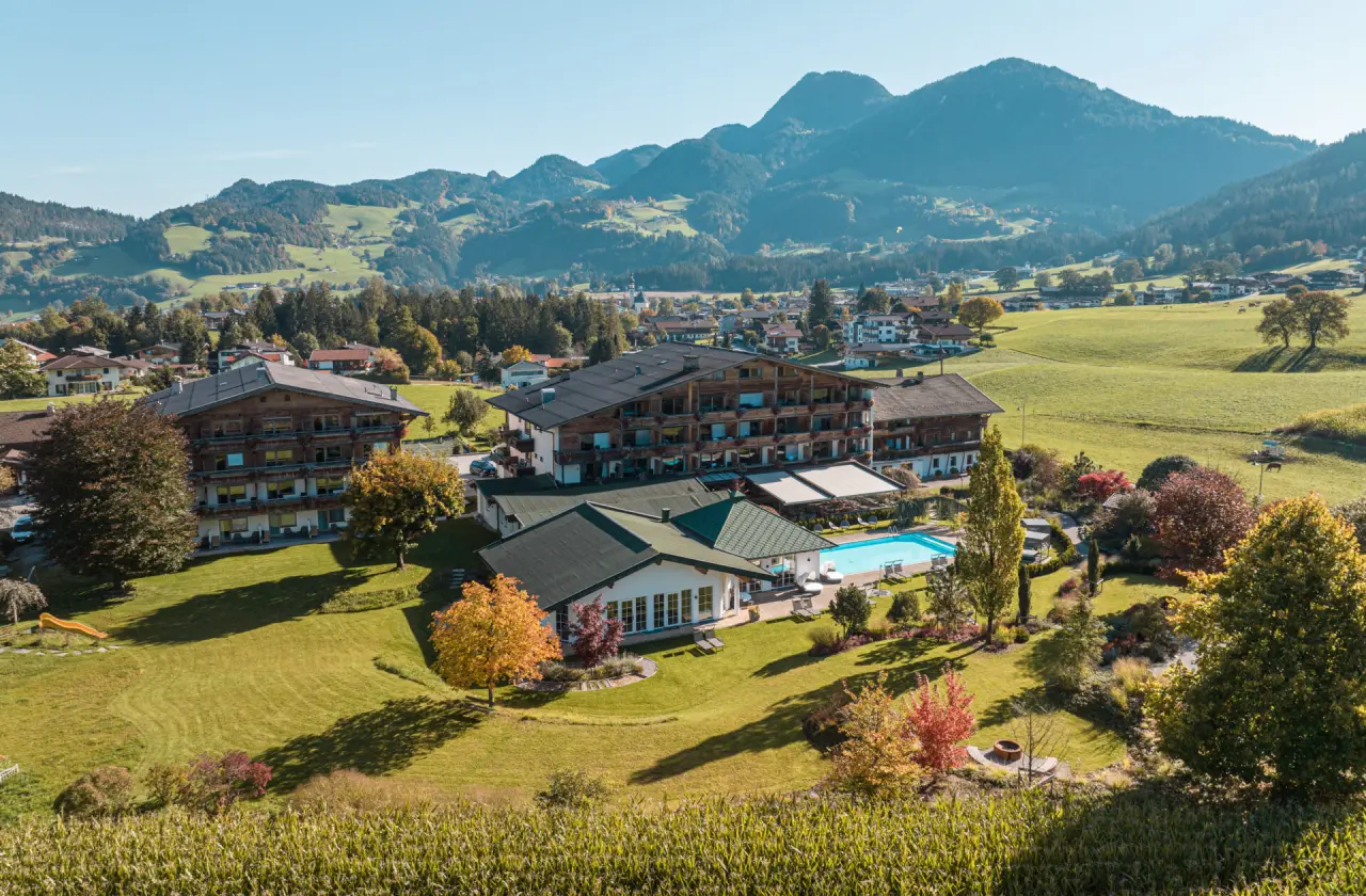 Luftaufnahme des Aktiv- & Wellnesshotel Pirchnerhof mit Aussenpool und Bergpanorama in der Tiroler Natur.