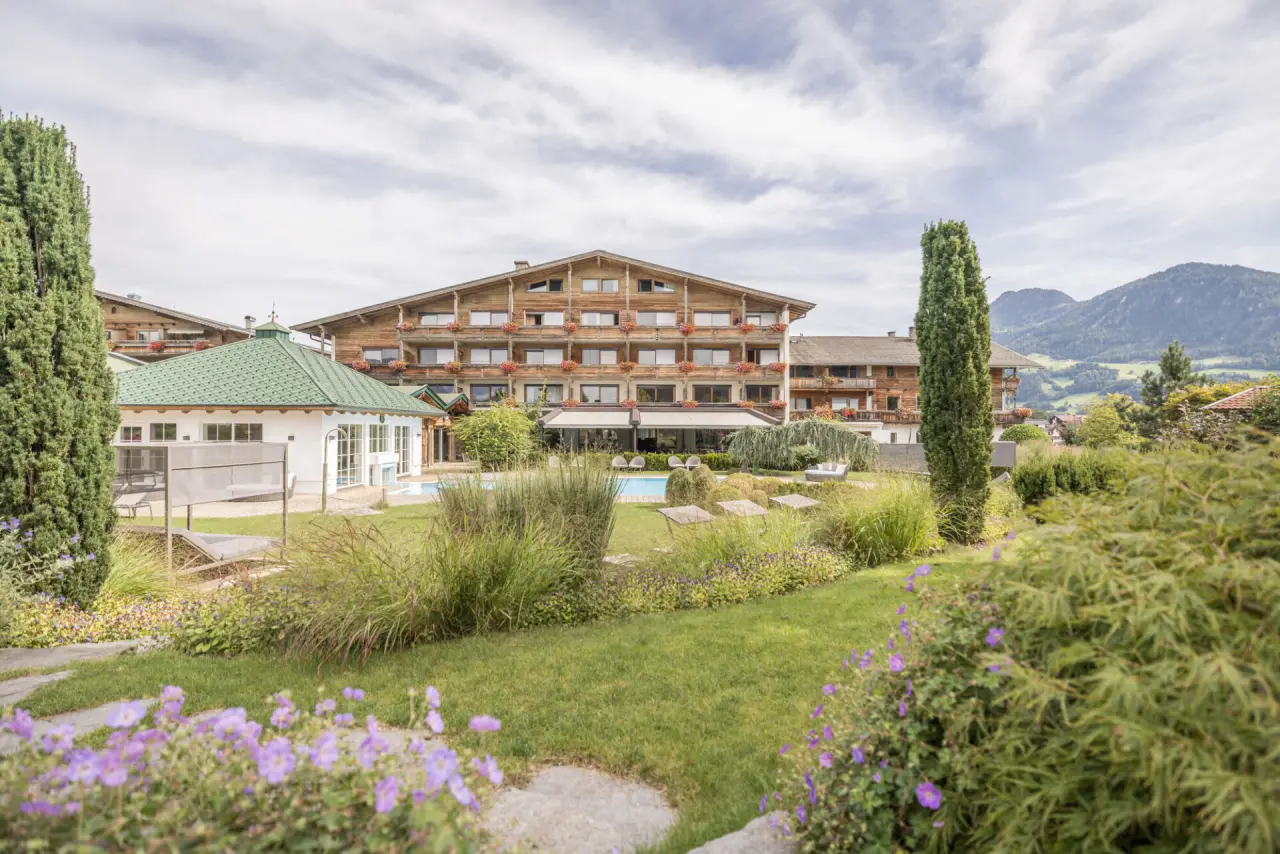 Aussenansicht des Aktiv- & Wellnesshotel Pirchnerhof mit Poolbereich, gepflegtem Garten und Alpenblick.