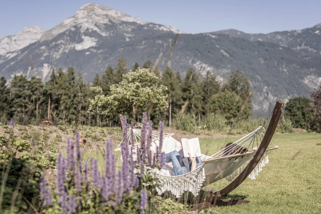 Gast entspannt in Hängematte im Hotelgarten mit Alpenpanorama im Aktiv- & Wellnesshotel Pirchnerhof.