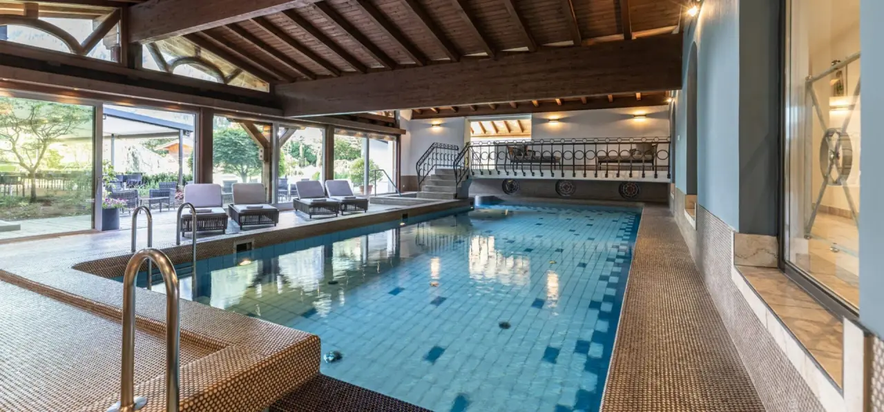 Grosszügiger Innenpool mit Holzdecke und Zugang zum Garten im Aktiv- & Wellnesshotel Pirchnerhof.