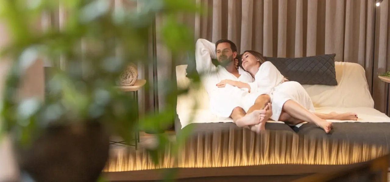 Entspannendes Paar in Bademänteln auf einer Liege im Ruheraum des Aktiv- & Wellnesshotel Pirchnerhof.