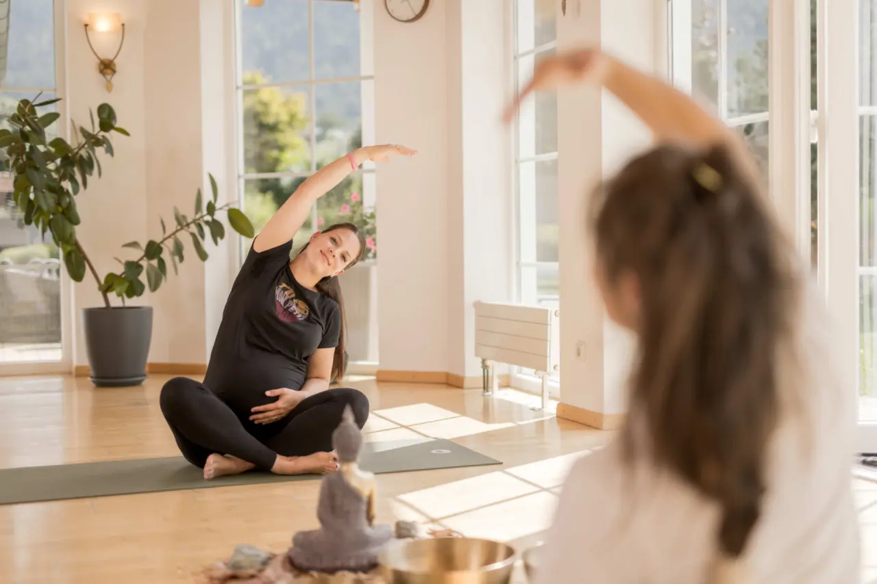 Schwangere Frau beim Yoga in einem hellen Raum mit Bergblick im Aktiv- & Wellnesshotel Pirchnerhof.
