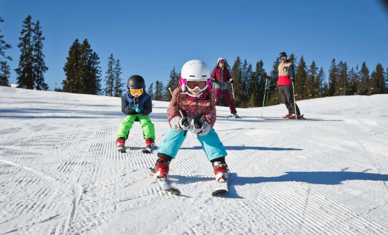 Familie beim Skifahren auf einer sonnigen Piste in den Bergen, ideal für Winterurlaub im Hotel Hasenauer.