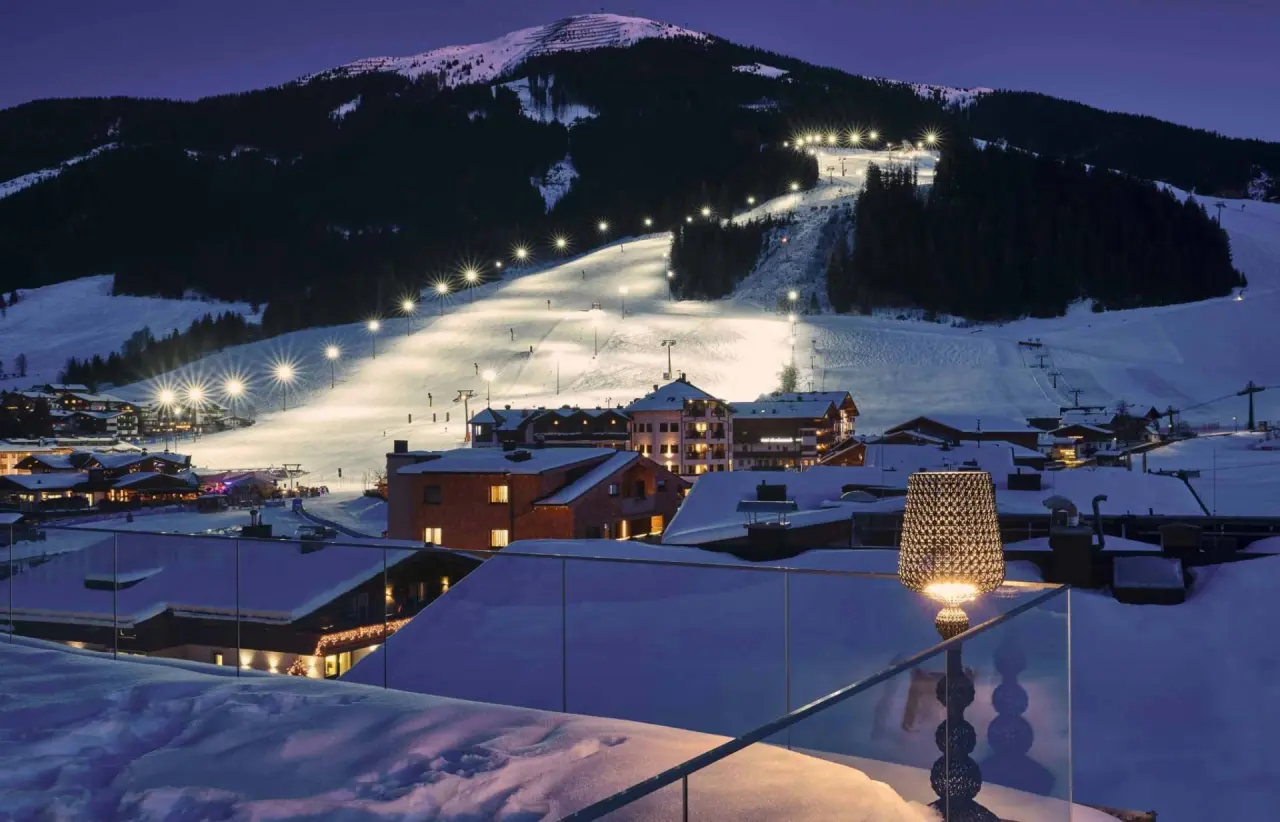 Hotel Hasenauer bei Nacht mit beleuchteter Skipiste und verschneiter Berglandschaft in Saalbach Hinterglemm.