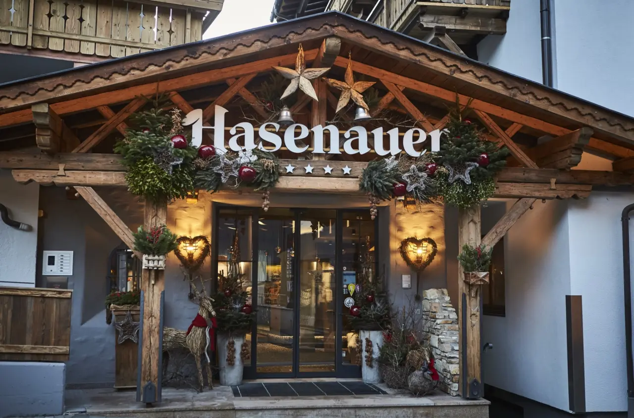 Festlich geschmückter Eingangsbereich des Hotel Hasenauer im Winter mit traditioneller Holzarchitektur und warmen Lichtern.