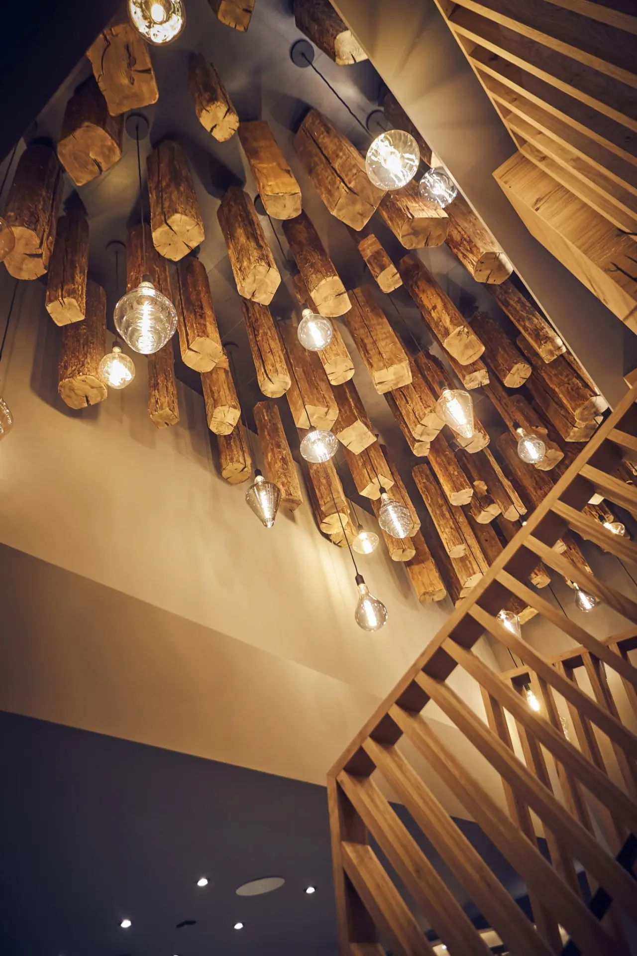 Einzigartige Deckenbeleuchtung mit rustikalen Holzbalken und modernen Glühbirnen im Hotel Hasenauer.