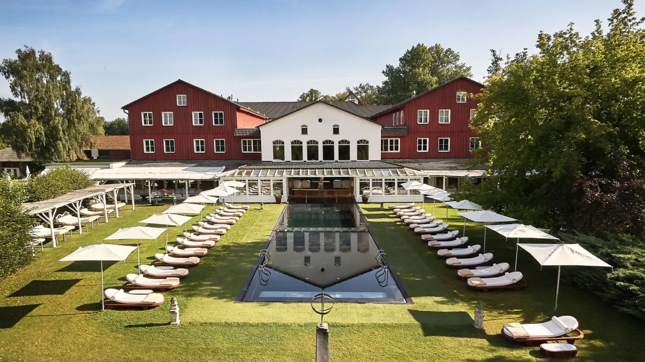 Panoramablick auf das Bleiche Resort & Spa mit rotem Haupthaus, großem Außenpool und sonniger Liegewiese.